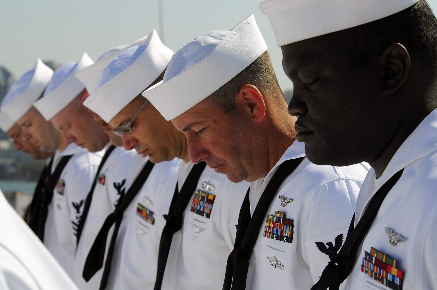 Chief petty officer selectees bow their heads in prayer on the flight deck, 9/11 remembrance.